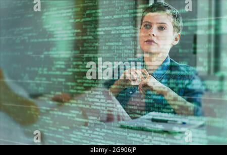 Female professional looking at binary codes on glass at office Stock Photo