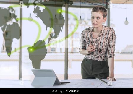 Female entrepreneur holding eyeglasses while leaning at desk in office Stock Photo