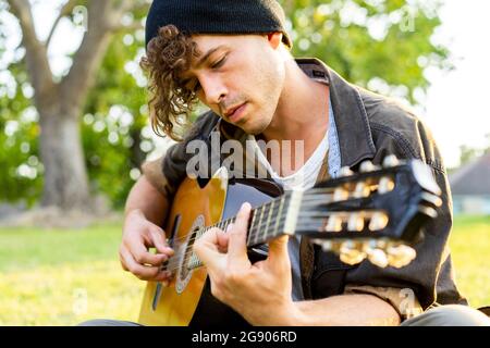 Handsome young man playing guitar at park Stock Photo