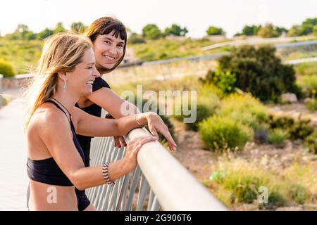 Cheerful mature female friends standing together on boardwalk Stock Photo