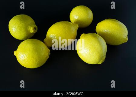 A group of fresh large ripe yellow lemons on a dark table top. Stock Photo