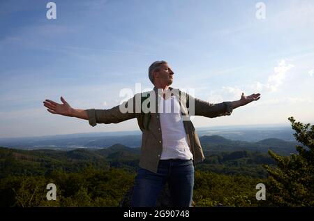 Male hiker standing with arms outstretched Stock Photo