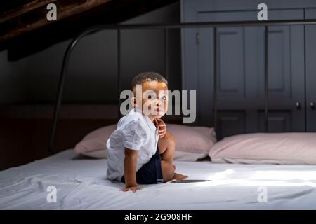 Cute boy sitting on bed in attic at home Stock Photo