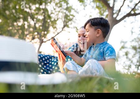 Smiling grandmother telling story to grandson in park during sunset Stock Photo