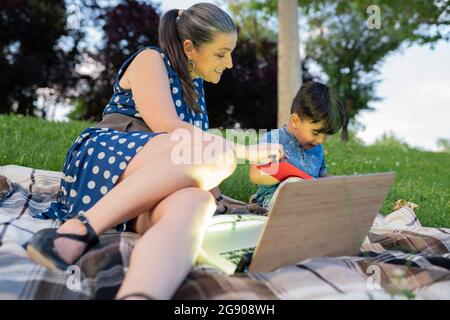 Grandmother telling story to grandson in park during sunset Stock Photo