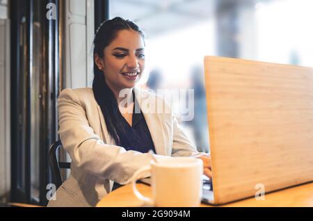 Businesswoman holding digital tablet with QR code and welcome text in coffee shop Stock Photo