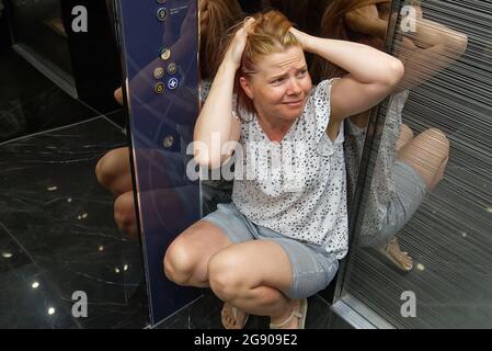Woman With Claustrophobia In Elevator. Claustrophobia in small space concept Stock Photo