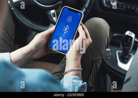 Woman accessing bluetooth on mobile phone in car Stock Photo