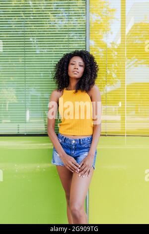 Young woman standing in front of green and yellow window Stock Photo