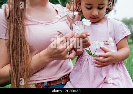 Mother and daughter holding flowers in park Stock Photo