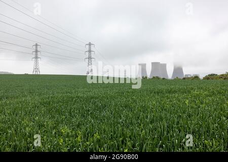 UK, England, Rugeley, Field with electricity pylons and cooling towers in background Stock Photo