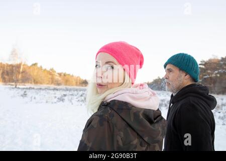 Woman looking over shoulder while standing by man during winter Stock Photo