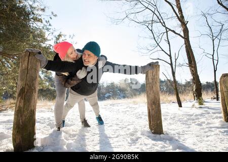 Smiling woman embracing man exercising on snow Stock Photo