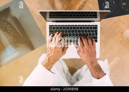Senior male doctor using laptop in clinic Stock Photo