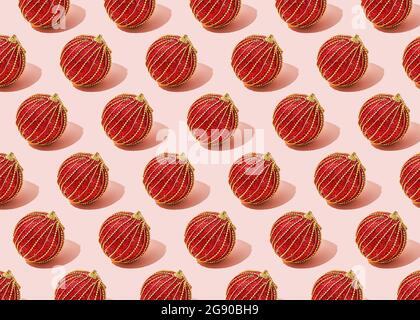 Pattern of red Christmas ornaments flat laid against pink background Stock Photo