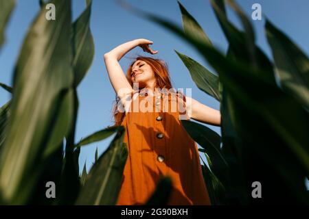 Smiling young woman enjoying in corn field Stock Photo