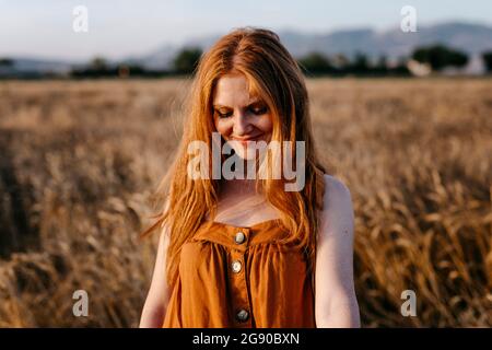Young woman looking down in field Stock Photo