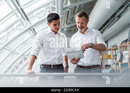Male professional team reading document while standing in office Stock Photo