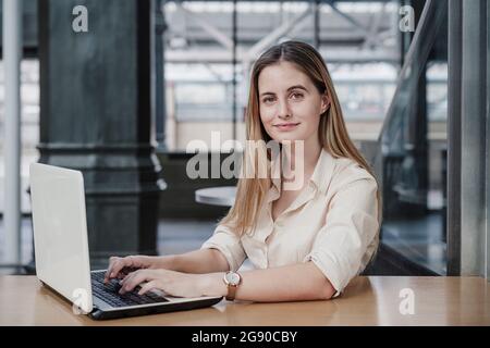 Beautiful young businesswoman sitting with laptop in cafe Stock Photo