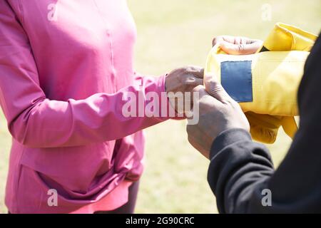 Man putting boxing glove in woman's hand on sunny day