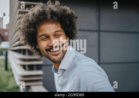 Young man with curly hair looking away while laughing Stock Photo