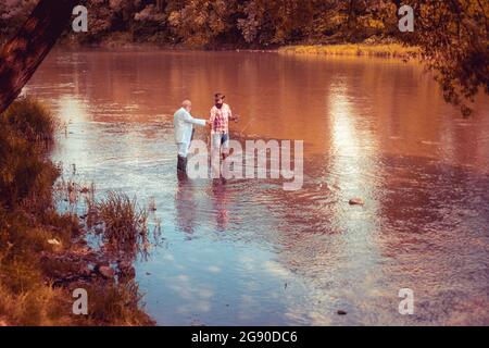 Brutal bearded men stand in river water with rod. Giving your hobby. Family time. Pothunter. Summer weekends or vacation. Happy fishermen in water. Ke Stock Photo