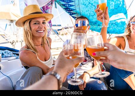 Happy male and female friends raising toast while sitting on yacht Stock Photo