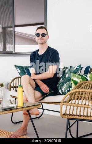Handsome man sitting on sofa at patio Stock Photo