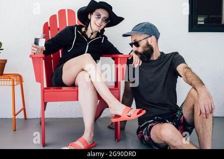 Bearded man kissing woman's hand sitting on chair in patio Stock Photo