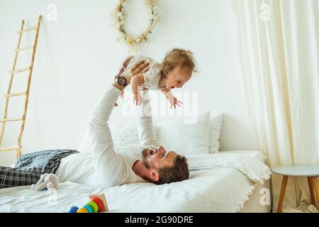 Playful man playing with daughter on bed at home Stock Photo