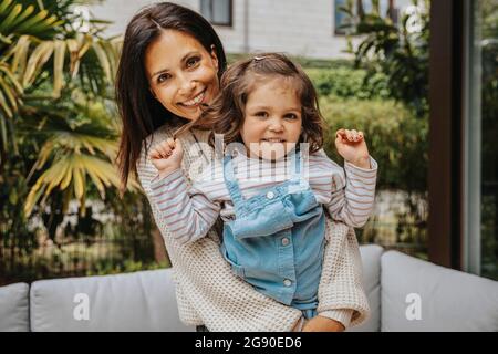 Happy woman embracing daughter from behind at backyard Stock Photo