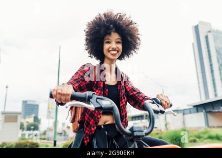 Young woman smiling while riding bicycle Stock Photo