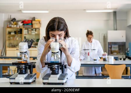 Female scientist looking through microscope at laboratory Stock Photo