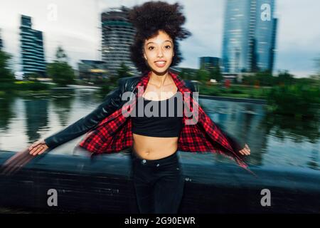Smiling woman spinning with arms outstretched in city