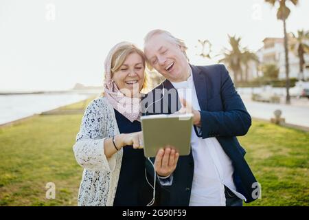 Mature couple laughing while watching video through digital tablet Stock Photo