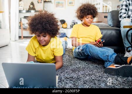 Twin brothers using wireless technologies at home Stock Photo