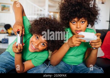 Excited twin brothers playing video game at home Stock Photo