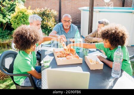 Multi-ethnic family enjoying snacks on table in back yard Stock Photo