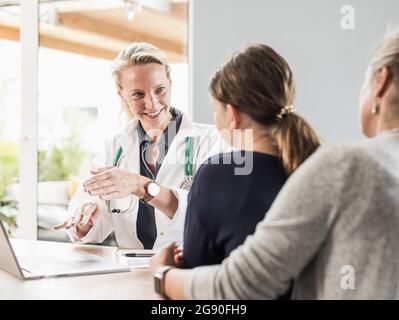 Smiling doctor giving advice to patient and woman at office Stock Photo