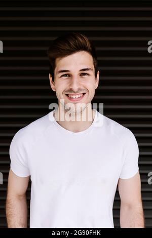 Happy young man standing in front of shutter Stock Photo