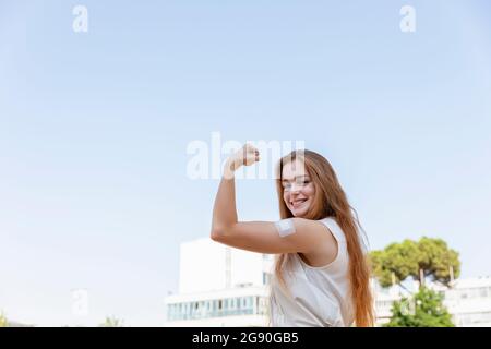 Beautiful female freelancer flexing muscles by sky Stock Photo