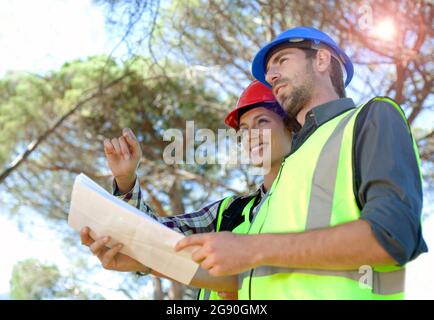 Female engineer discussing with male colleague holding document Stock Photo