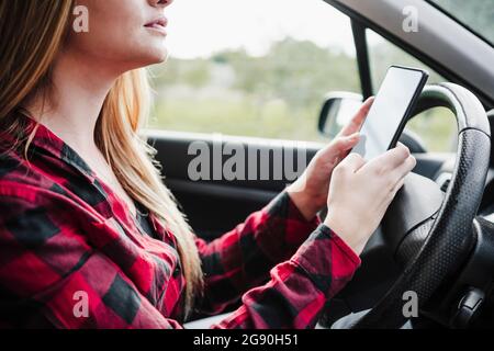 Young woman using smart phone in car Stock Photo