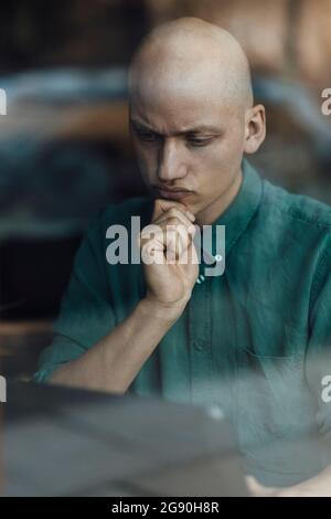 Male cafe owner with hand on chin using digital tablet Stock Photo