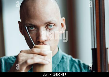 Male cafe owner staring while drinking coffee Stock Photo