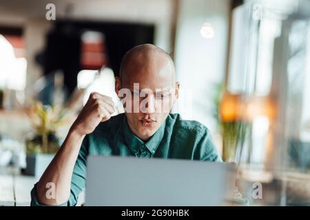 Male cafe owner cheering while using laptop Stock Photo