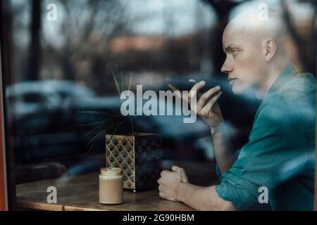 Male entrepreneur talking on mobile phone at cafe Stock Photo