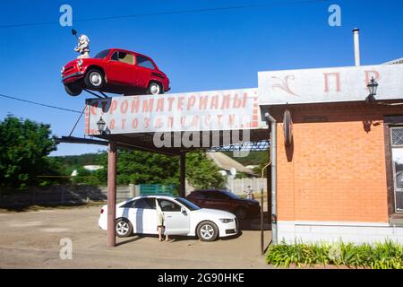 Old red soviet Zaporozhets car on the roof of construction supplies and auto spare parts store in Kharkov industrial mega city in the East of Ukraine. Stock Photo