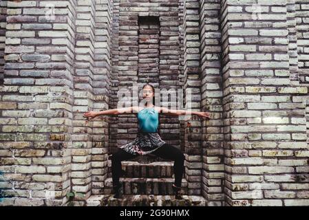 Female dancer doing balancing exercise amidst stone walls Stock Photo