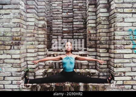 Smiling young woman doing the splits on steps Stock Photo